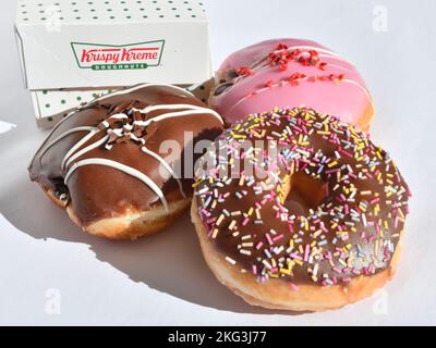 Una selezione di ciambelle Krispy Kreme con logo box. Foto Stock