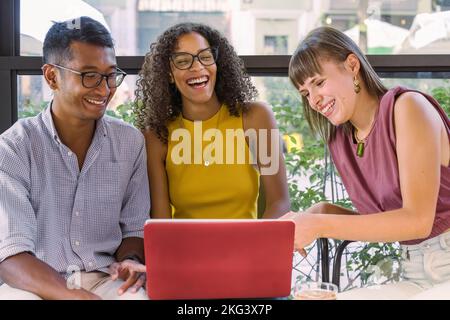 ritratto di tre studenti entusiasti che leggono buone notizie sul computer, giovani che usano il laptop per studiare on line, amici di generazione z che si divertono Foto Stock