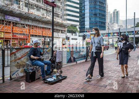 La gente cammina accanto a un musicista che suona "Glory to Hong Kong" e "Do you here the People Sing?" Su un erhu di fronte alla Stazione di Quarry Bay a Hong Kong. "Glory to Hong Kong”, considerato un inno non ufficiale delle proteste a favore della democrazia del 2019, ha fatto notizia ultimamente perché è stato scambiato per l'inno nazionale cinese in occasione di numerosi eventi internazionali di rugby. A Hong Kong, permangono dubbi circa la legalità di suonare o di eseguire questa canzone in pubblico ai sensi della legge sulla sicurezza nazionale. (Foto di ben Marans/SOPA Images/Sipa USA) Foto Stock