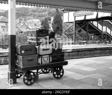 Bagagli vintage in attesa sul binario della stazione ferroviaria di Llangollen, Llangollen, Denbighshire, Galles, Regno Unito Foto Stock