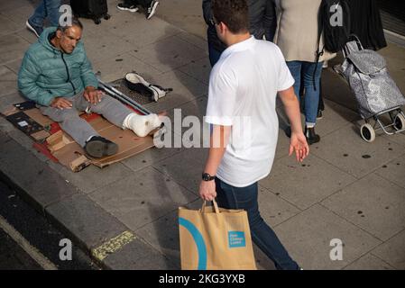 Uomo senza casa che indossa una gamba gettata su un marciapiede di Londra Foto Stock