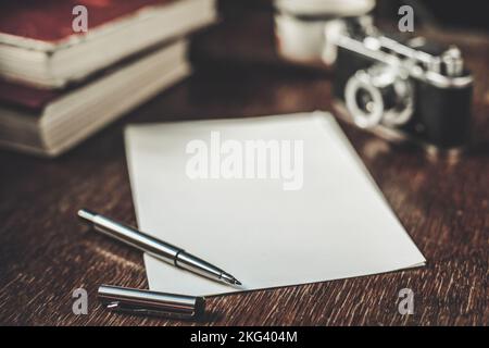 Scrivere una storia. Fogli di carta, penna, macchina fotografica retrò e libri su tavola di legno Foto Stock