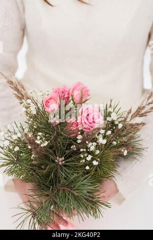 una donna tiene in mano un bouquet di fiori, un primo piano di un bouquet invernale Foto Stock