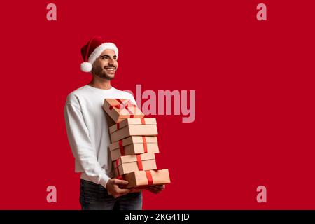 Bell'uomo arabo a Santa Hat con Stack of Gifts in Hands Foto Stock