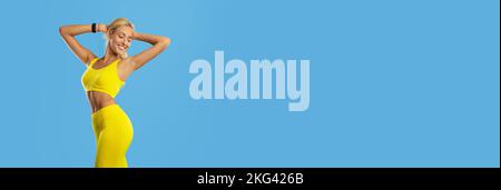 Annuncio fitness. Bella donna atletica in elegante Sportswear isolato su sfondo blu Foto Stock