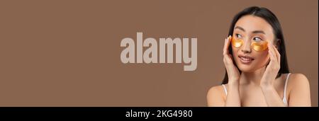 Bella donna coreana sorridente con patch sotto gli occhi guardando Copy Space Foto Stock