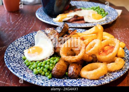 Un grande pasto alla griglia misto JD Wetherspoons servito con anelli di cipolla e un uovo fritto. Il rapporto qualità/prezzo è su un tavolo da pub in un pub Wetherspoons Foto Stock