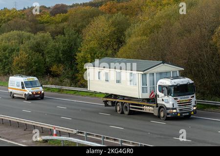 HGV trasporto di una casa mobile lungo l'autostrada M3, carico ampio, Inghilterra, Regno Unito, carico ampio con veicolo di scorta che viaggia dietro Foto Stock