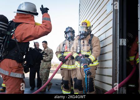 Un pompiere con la forza giapponese di autodifesa aerea, a sinistra, comunica una situazione attuale a Airman 1st Classe Jeremy Linger, 374th Civil Engineer Squadron pompiere, a destra, e il personale Sgt. Douglas Martin, 374th° ingegnere civile Squadron, responsabile vigili del fuoco, al centro, durante un addestramento bilaterale alla base aerea di Yokota, Giappone, 28 ottobre 2022. Il CES e il JASDF del 374 si esercitano ogni anno per dare a entrambi la possibilità di imparare l'uno dall'altro provando diverse attrezzature e metodi di prevenzione degli incendi. Foto Stock