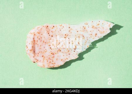 Grana macchia cosmetica. Strofinare la macchia con l'estratto di albicocca e pesca su fondo verde. Prodotto naturale per la cura della pelle per esfoliazione e peeling Foto Stock