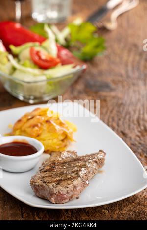 bistecca su un piatto con patate gratinate Foto Stock