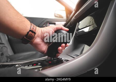 La mano del conducente mette la leva del cambio per cambiare la posizione del cambio automatico nella vettura. Foto Stock