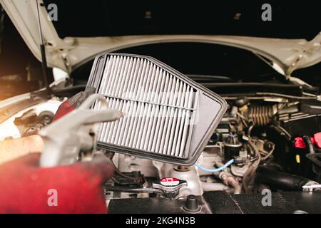 Pulizia del filtro dell'aria per auto con pistola ad aria compressa a mano meccanica nel garage di riparazione auto. Foto Stock