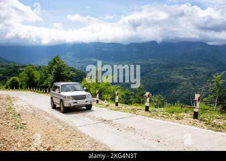 Fuoristrada 4x4 che guida su una strada di ghiaia in salita verso la cima del Monte Khvamli nella verde lussureggiante valle di Tskhenistsqali nella regione di Racha in Georgia. Foto Stock