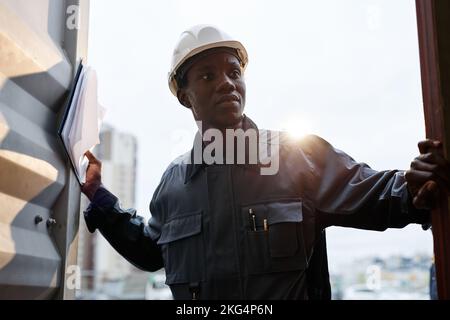 Ritratto retroilluminato di un lavoratore maschio che indossa lo sportello del contenitore con apertura in elmetto nelle banchine di spedizione, spazio per le copie Foto Stock