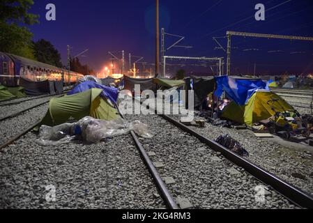 Lunga esposizione di città tenda improvvisata sui binari ferroviari di notte. Campo profughi/migranti di transito al confine greco-macedone settentrionale. Foto Stock
