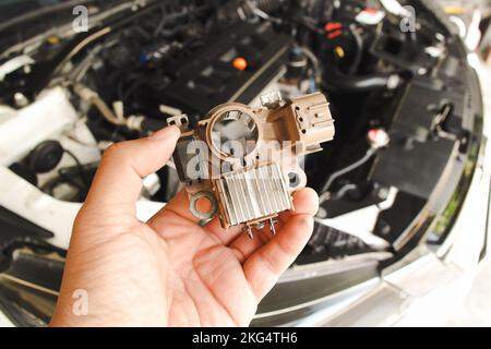 Vecchio raddrizzatore alternatore per auto tenere da mano meccanica auto con vano motore auto sfondo sfocato Foto Stock