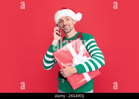 elfo allegro parlare al telefono. uomo in babbo natale cappello saluto on-line al telefono Foto Stock