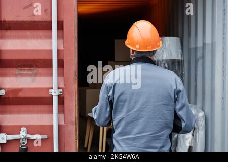 Immagine sul retro del lavoratore che indossa contenitori per il controllo in elmetto presso il molo di spedizione, spazio per le copie Foto Stock