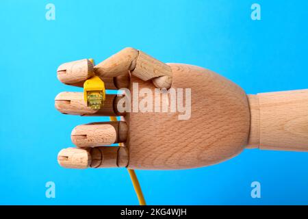 Immagine concettuale di una mano di legno che tiene un cavo patch a banda larga per internet Foto Stock