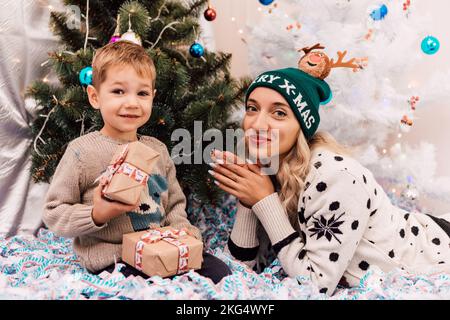 Madre e figlio scambiano regali vicino all'albero di Natale. Regali di Natale Foto Stock