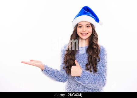 Inverno ragazza teen che punta sulla scpace della copia. Foto ritratto di felice giovane adolescente in inverno maglione isolato su sfondo bianco. Foto Stock