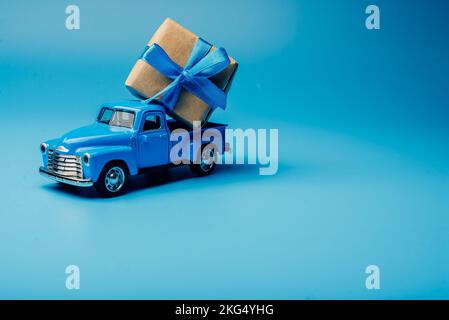 L'auto giocattolo è caricata con un regalo. minimalismo in blu Foto Stock