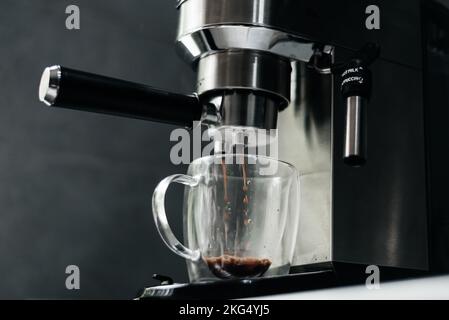 Macchina per il caffè che riempie una tazza di espresso. Tazza trasparente in macchina per caffè automatica. Bevanda per la prima colazione Foto Stock