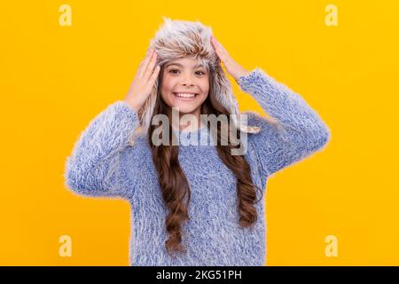 bambino felice in maglione e cappello con copertura sull'orecchio su sfondo giallo, infanzia Foto Stock