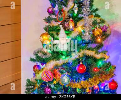 Albero di Natale decorato su sfondo bianco parete nell'angolo della stanza Foto Stock