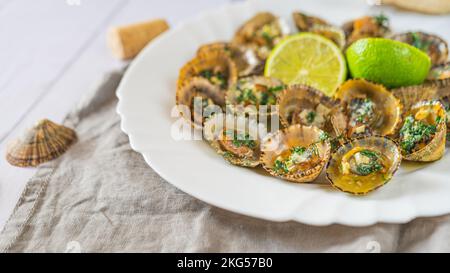 Molluschi di limbano con calce su piatto bianco Foto Stock