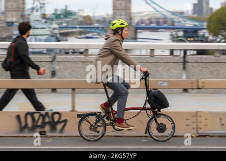 Un uomo che si spostò durante l'ora di punta su una bicicletta elettrica pieghevole Brompton lungo il London Bridge, Londra, Regno Unito. 17 Nov 2022 Foto Stock