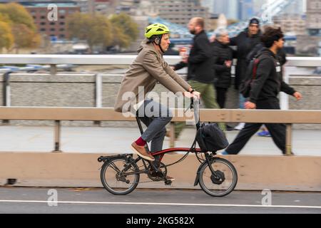 Un uomo che si spostò durante l'ora di punta su una bicicletta elettrica pieghevole Brompton lungo il London Bridge, Londra, Regno Unito. 17 Nov 2022 Foto Stock