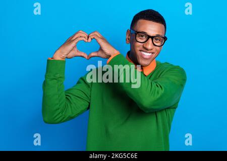 Primo piano foto di giovane studente macho indossare formale verde jumper bel occhiali che mostra amore simbolo data sentimenti isolati su sfondo di colore blu Foto Stock