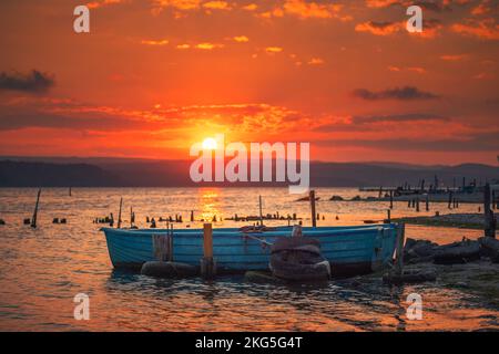 Tramonto sul lago, molo in legno e vecchia barca da pesca Foto Stock