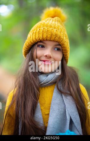 Ritratto di bella ragazza o giovane donna all'aperto nella foresta autunnale. Donna con cappello e sciarpa invernali. Foto Stock