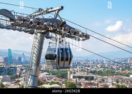 Closeup di funivia sui tetti di Tbilisi Georgia con la città sparsa al di sotto e le montagne in lontananza Foto Stock