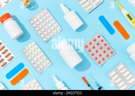 Termometro con diverse siringhe per medicinali su sfondo blu. Farmacia sanitaria e concetto di medicina Foto Stock