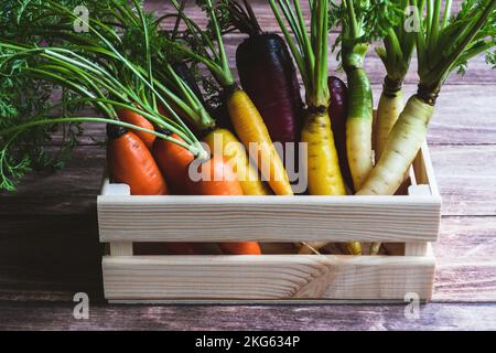 Carote colorate in cassetta di legno sul tavolo da cucina Foto Stock