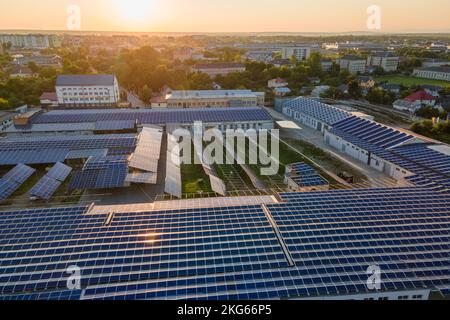 Vista aerea dei pannelli solari fotovoltaici blu montati sul tetto dell'edificio industriale per la produzione di elettricità ecologica verde la sera. Produzione di Foto Stock