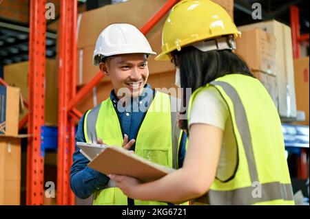 Esperto e professionale direttore di magazzino maschile asiatico millenario che parla e lavora con una giovane collega. concetto di ambiente di lavoro industriale Foto Stock