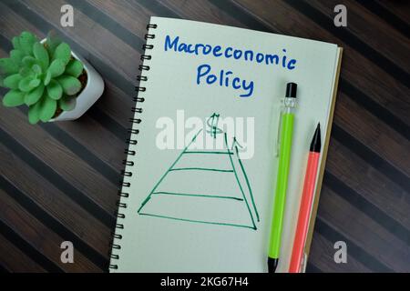 Concetto di politica macroeconomica scrivere su un libro isolato su tavola di legno. Foto Stock