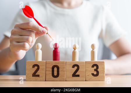 Mano che tiene dardo su persone rosse e 2023 anno blocks.Goal, piano, azione, obiettivo, strategia, Leadership, Capodanno e concetto di marketing Foto Stock