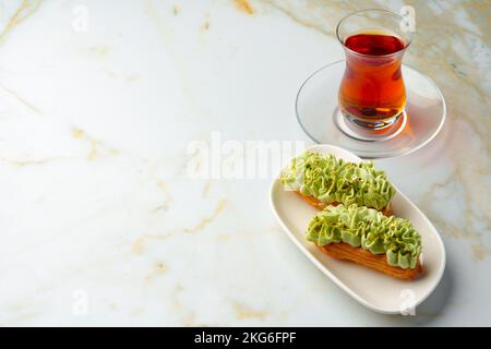 Torta Eclair con glassa al pistacchio su piatto bianco Foto Stock