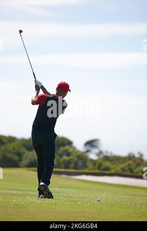 Lo shot non è finito fino a quando non si segue attraverso. Vista posteriore ripresa di un uomo in media golf swing. Foto Stock