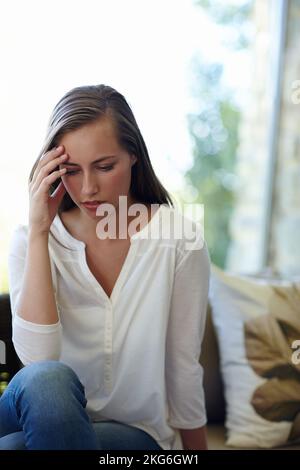 Vivere nell'età dell'ansia. Un taglio corto di una giovane donna stressata seduta nel suo salotto. Foto Stock
