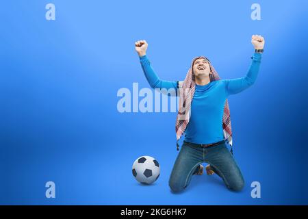 L'uomo asiatico con keffiyeh festeggia la vittoria con espressioni eccitate con sfondo colorato Foto Stock