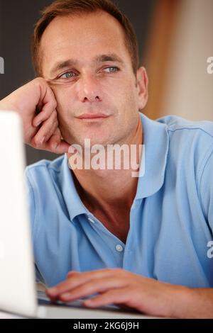 Aggiornamento dello stato... pensiero. L'uomo d'affari guarda attentamente in lontananza mentre lavora sul suo notebook. Foto Stock