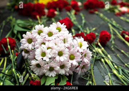 Fiori sul memoriale. Bouquet di fiori su lapide. Dettagli della cerimonia funebre. Foto Stock