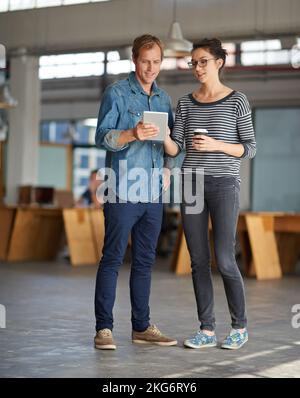 Controllo dell'agenda dei giorni. Un uomo che mostra qualcosa sul suo tablet digitale a un collega. Foto Stock